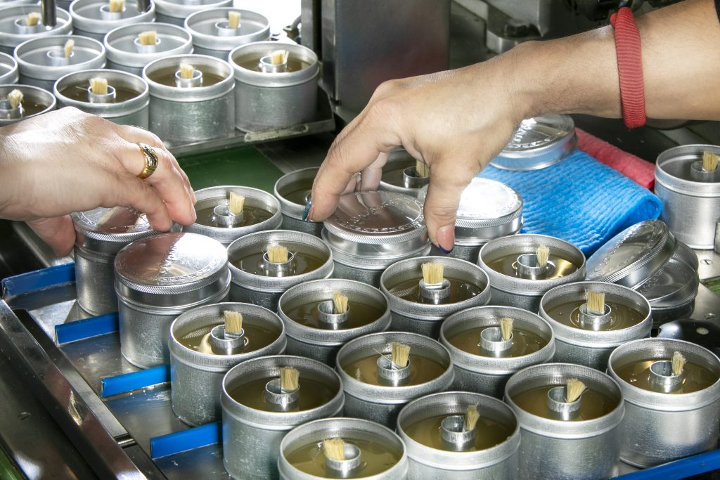 Produzione Coccoina: Sistemazione dei coperchi sui barattoli in alluminio della colla Coccoina in pasta